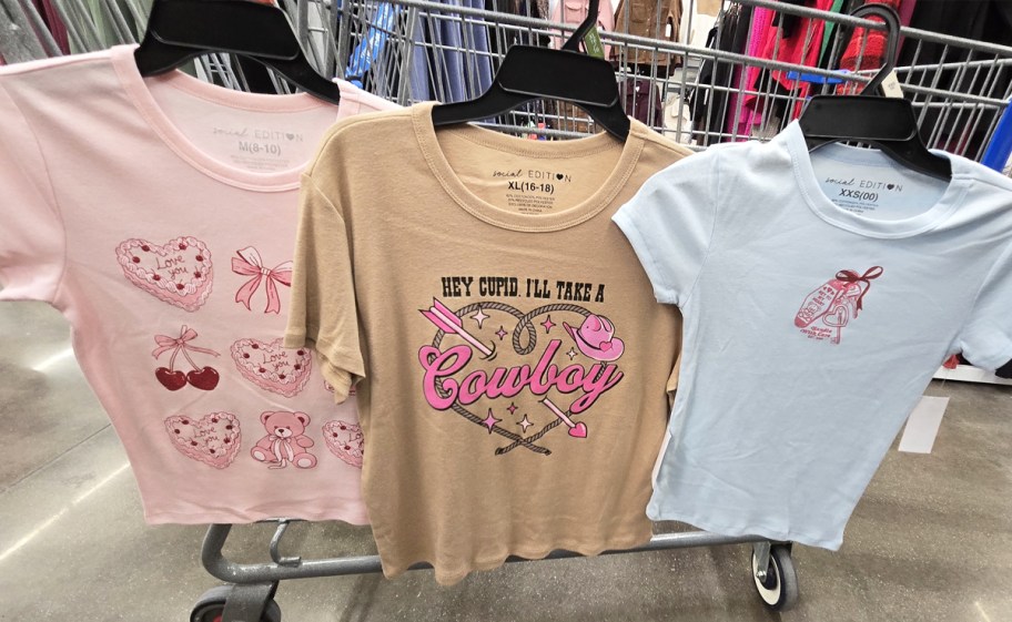 valentine themed graphic t-shirts hanging on cart in store