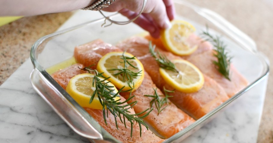 putting lemon slices and herbs over salmon