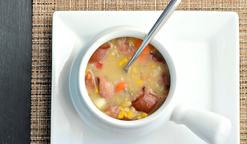 A bowl of corn and sausage chowder on the table.