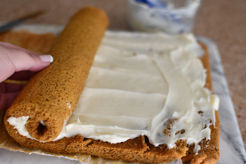 rolling up pumpkin roll with cream cheese frosting 