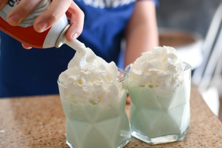 adding whipped cream to blended McDonald's shamrock shakes in cups