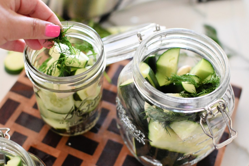 adding dill to jars of cucumbers