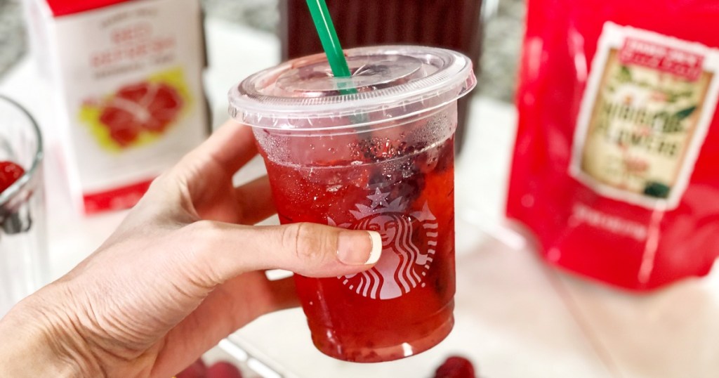hand holding red drink in starbucks cup