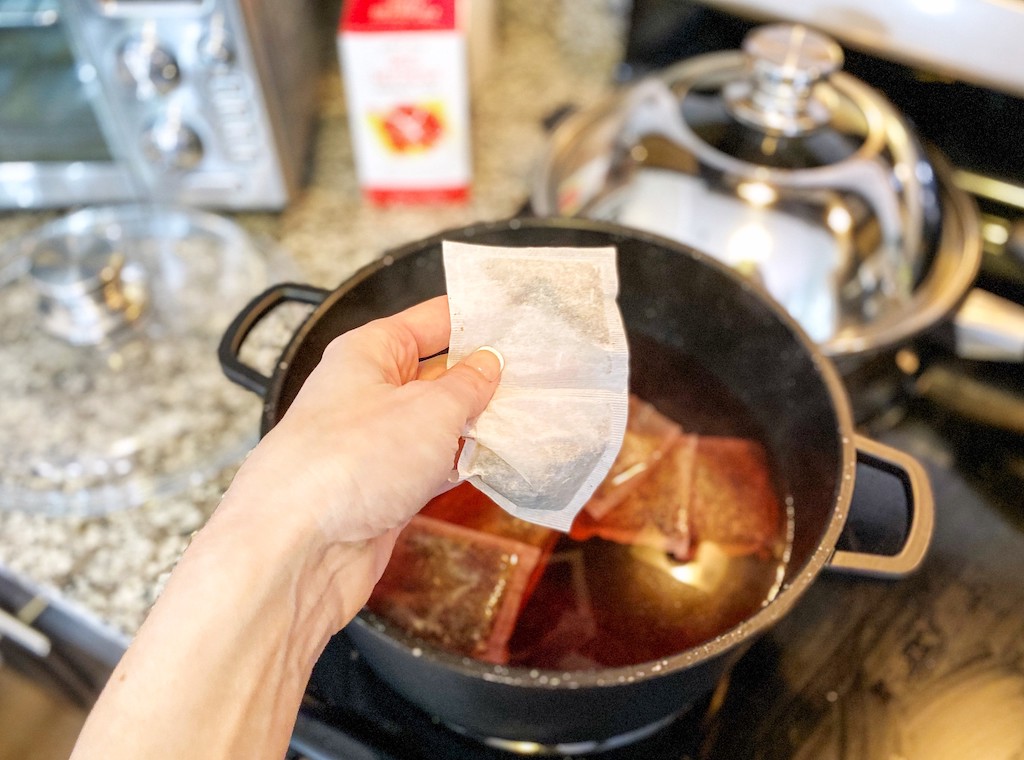putting tea bags in pot of water 