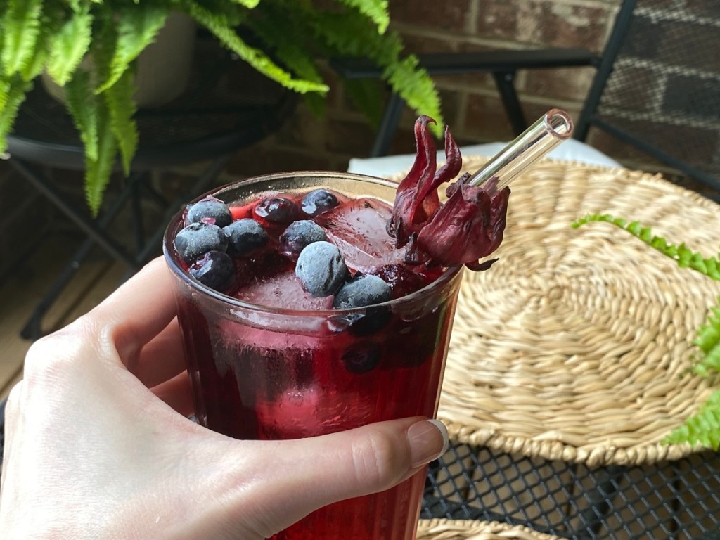 hand holding purple drink with berries and a straw