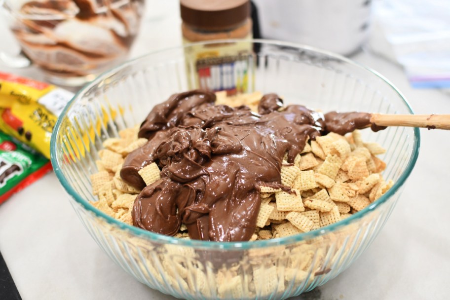 adding chocolate to chex cereal in a large bowl