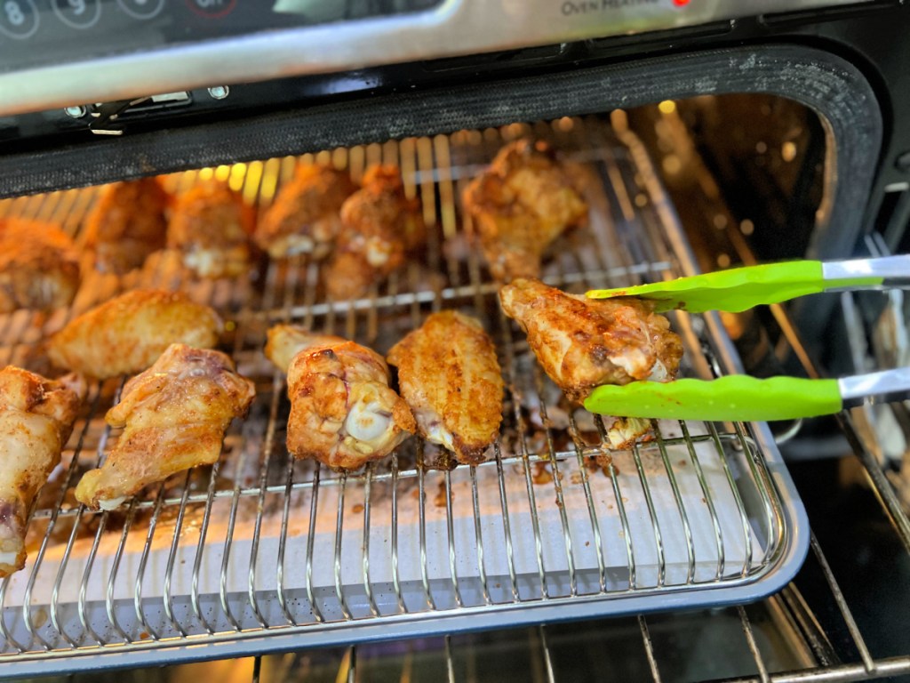 turning oven baked chicken wings with tongs