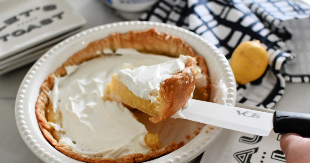 Cutting a slice of blender lemon pie with whipped topping .