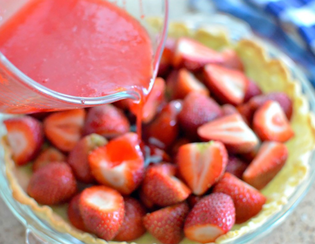 pouring gelatin over strawberries in crust