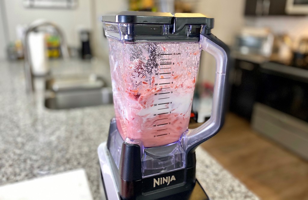 blender with strawberries, yogurt, and almond milk