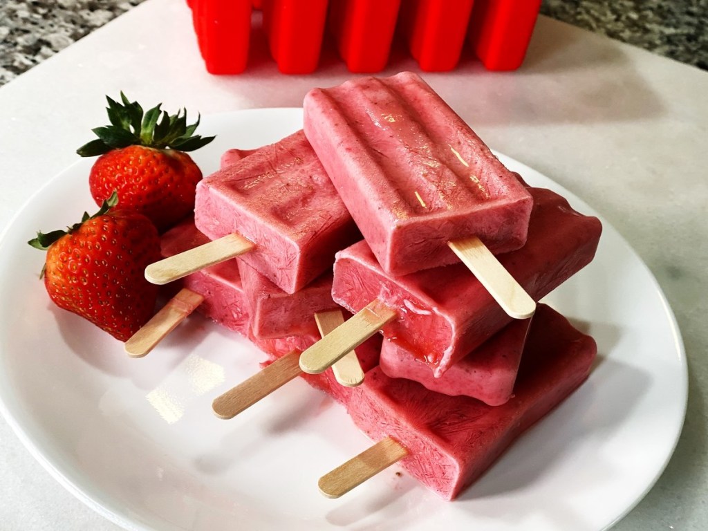 red popsicles on plate with strawberries