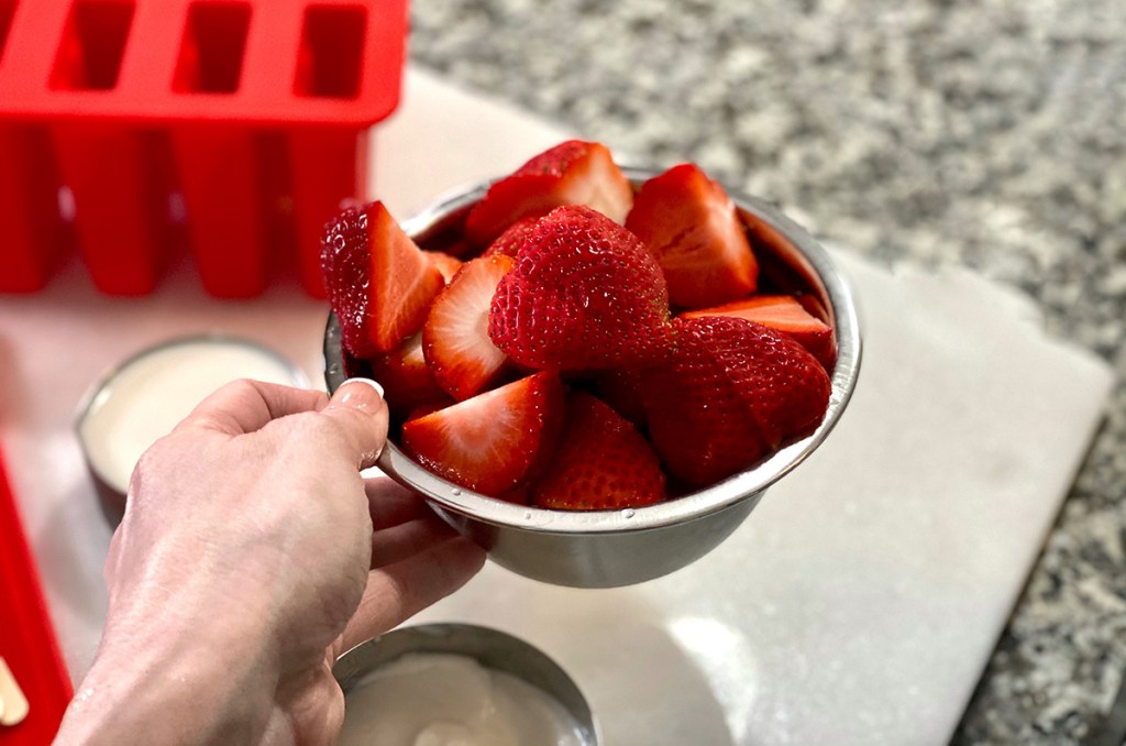 hand holding bowl of strawberries