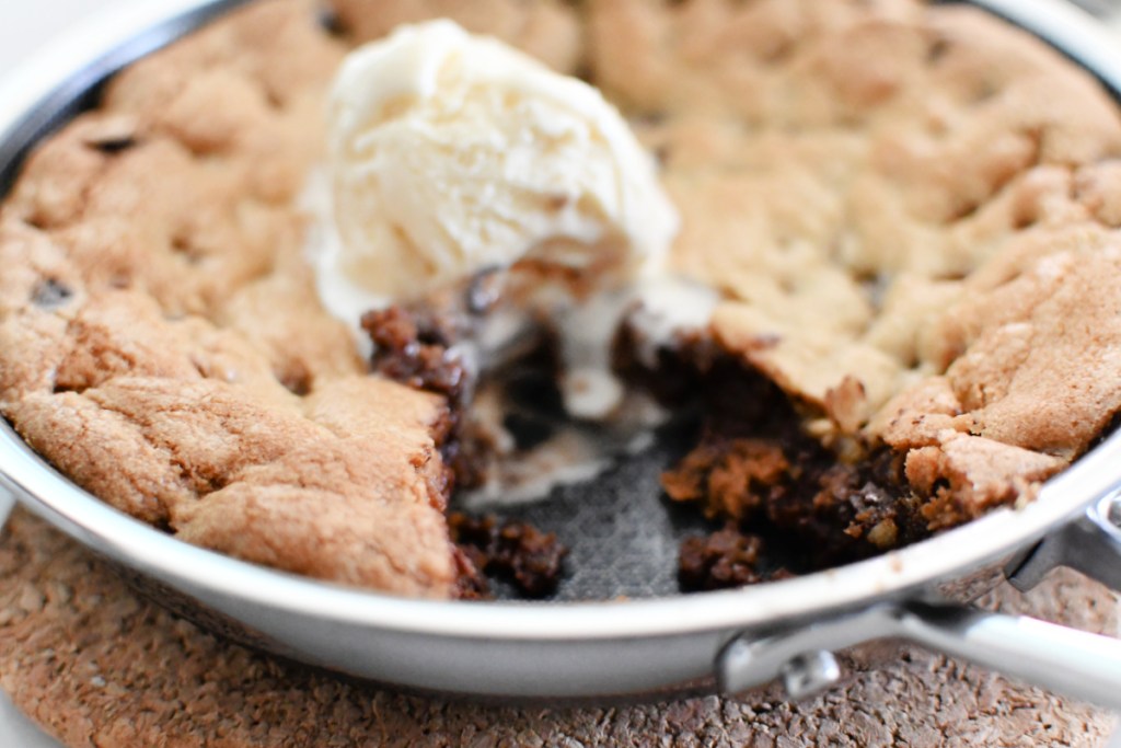 gooey chocolate chip cookie in a skillet with ice cream on top