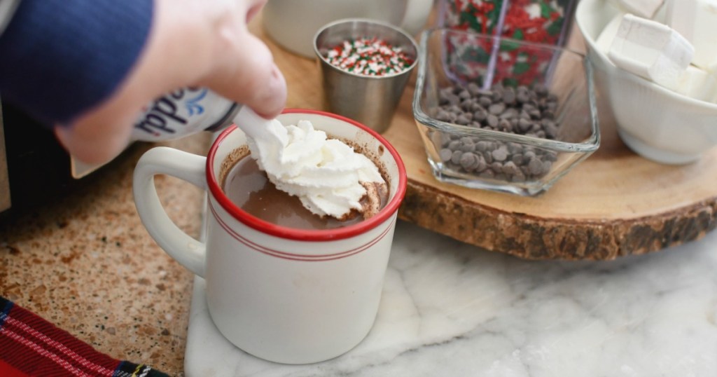 adding whipped cream to crock pot hot chocolate