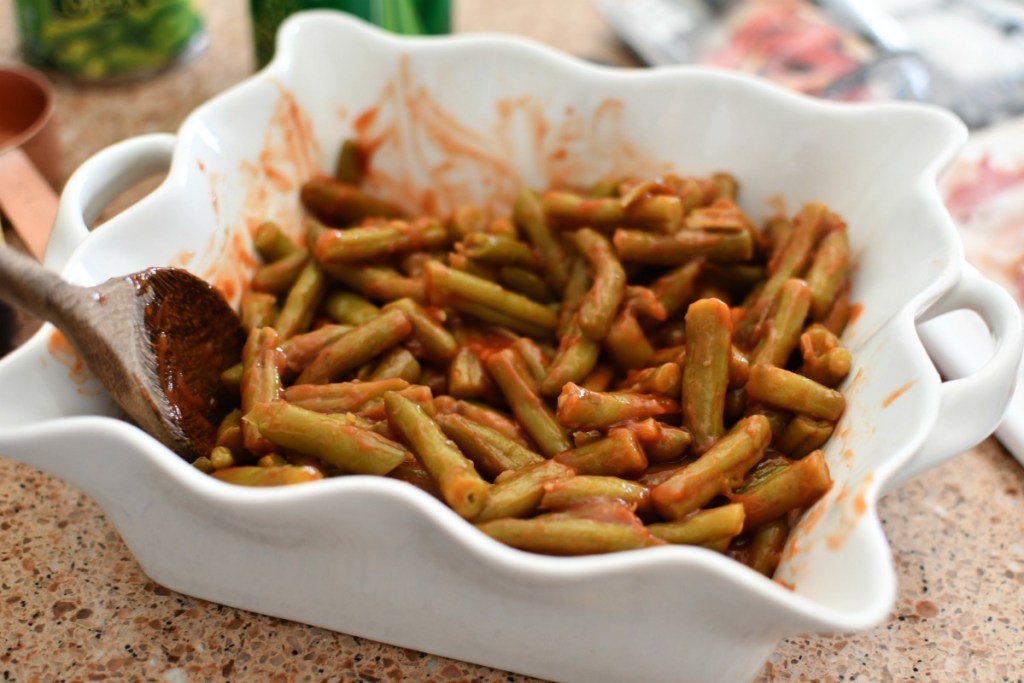 mixing green beans with worsheshire sauce and ketchup