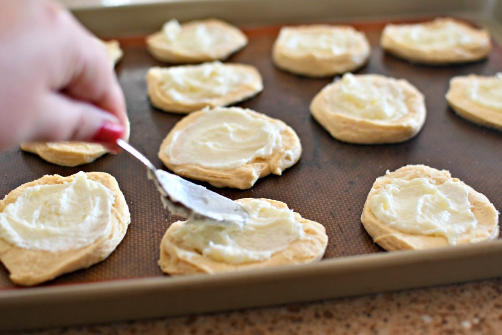 spreading cream cheese over biscuit cheese danish