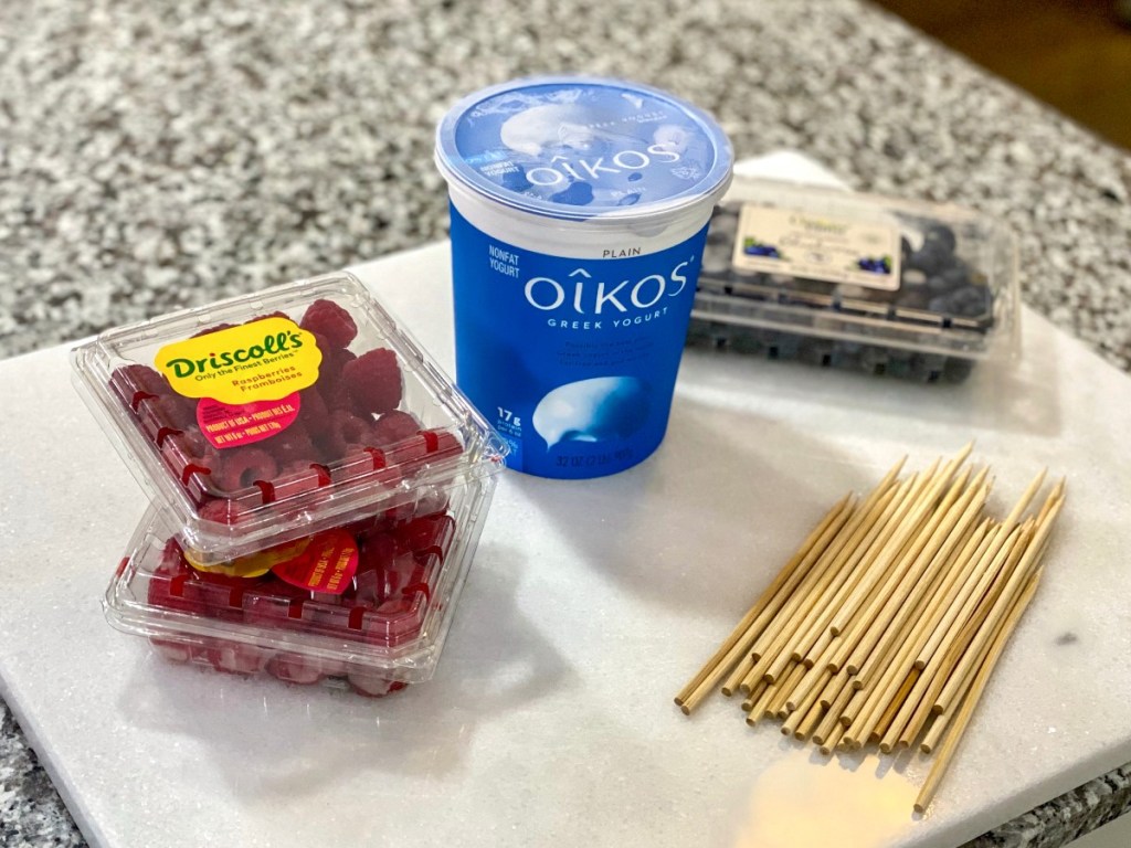 berries, yogurt, and skewers on white cutting board