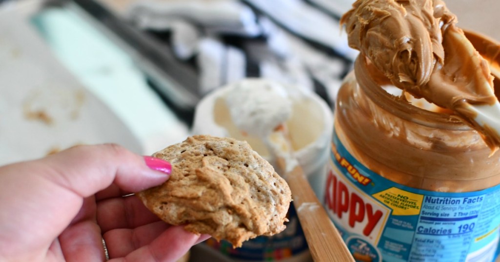 woman holding fluffernutter cookie with skippy peanut butter in the backgroud 