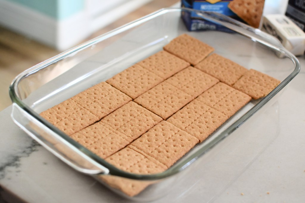 lining a baking pan with graham crackers