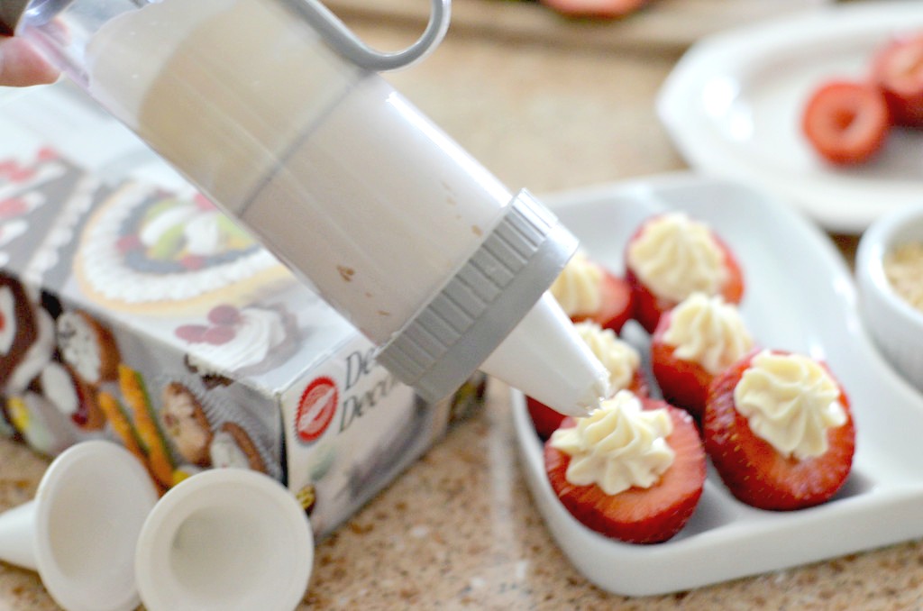 cheesecake stuffed strawberry dessert using wilton gadget to pipe frosting