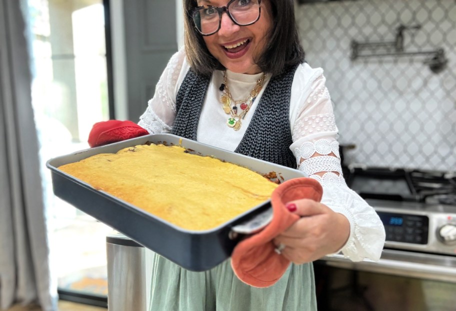 woman holding a casserole with chili and cornbread in a caraway bakeware pan 