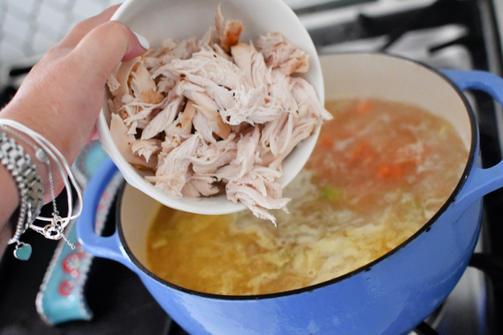 adding shredded chicken to chicken lemon orzo soup