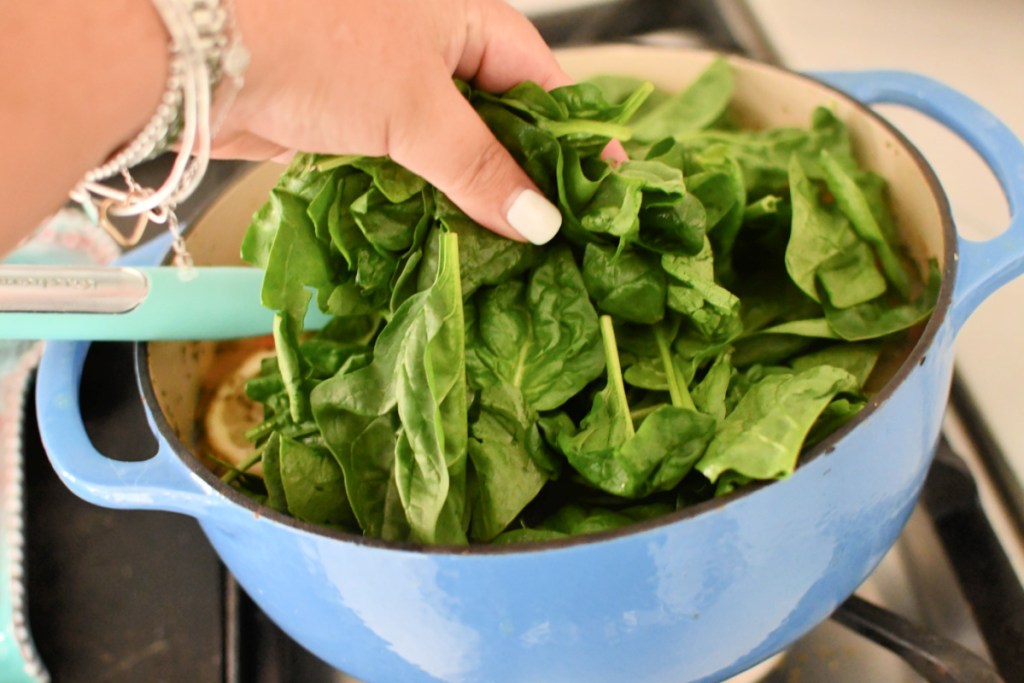 adding spinach to pot of hot chicken orzo soup
