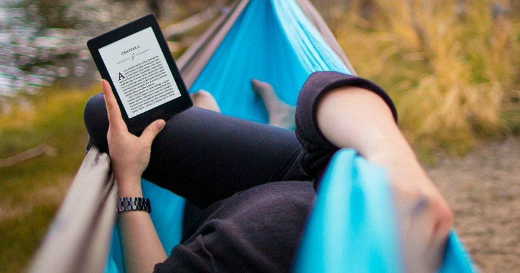 person in a hammock holding a kindle 