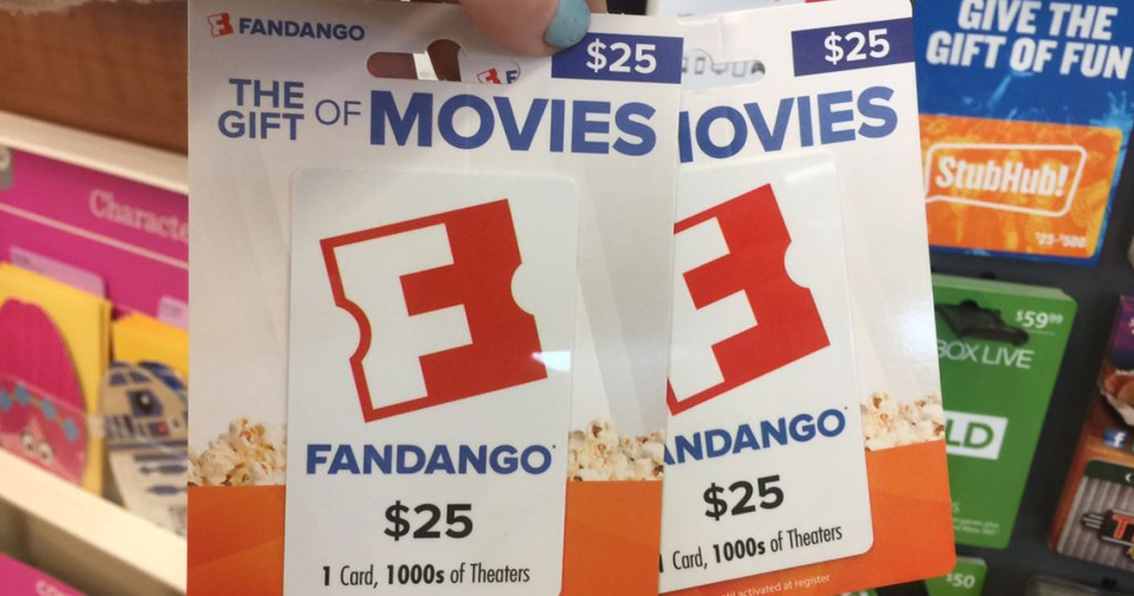 hand holding up two fandango gift cards in a store
