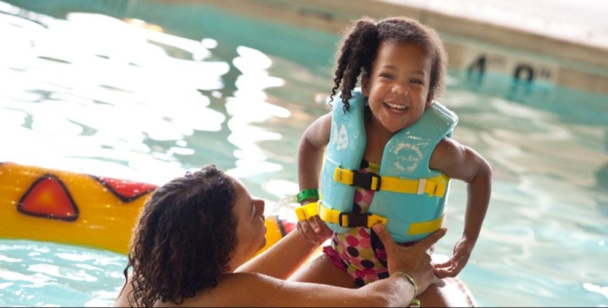 giant slide and pool and girl with life vest smiling