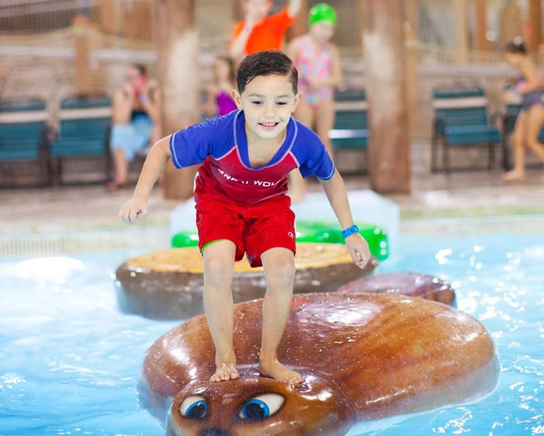 boy standing on toy in pool