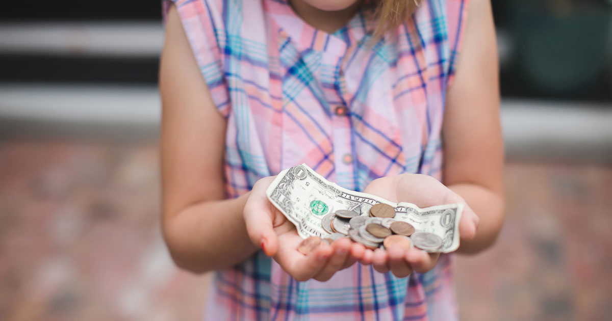 girl holding up change and dollar bill