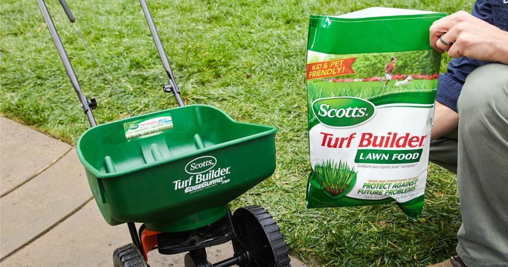 Person holding a bag of Scott's turf builder