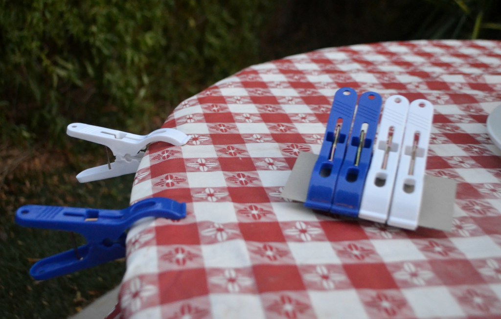 camping hacks - using clamps on table to hold down tablecloth