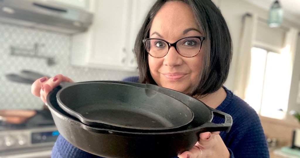 woman holding two black cast iron pans
