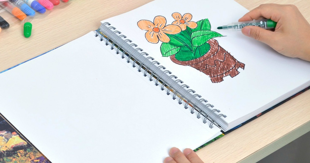 child coloring flowers in a sketch book