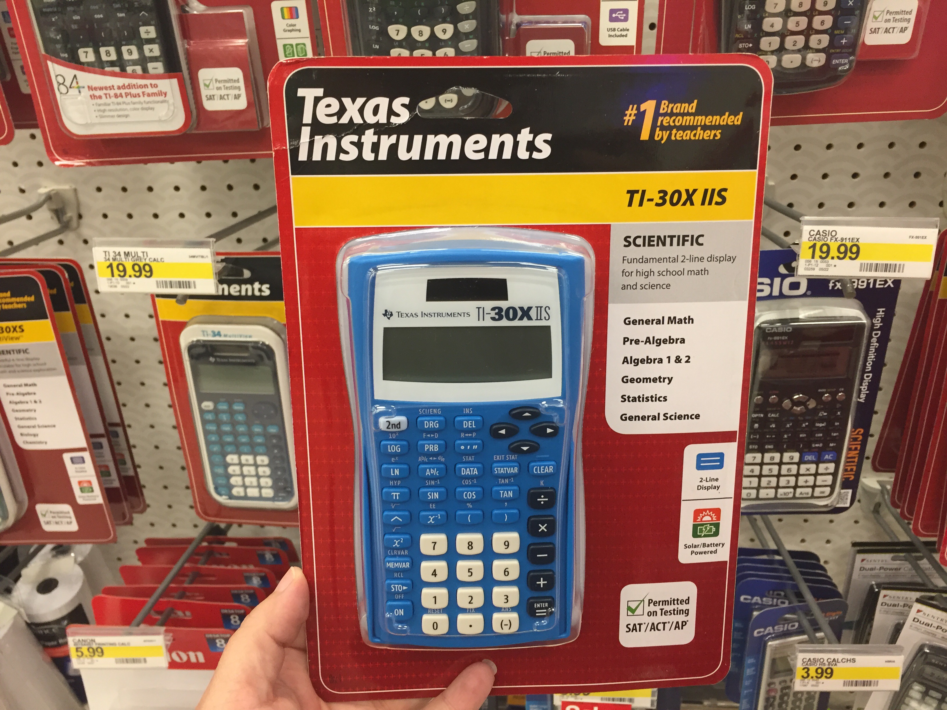 hand holding Texas Instruments TI-30X IIS 2-Line Scientific Calculator in store