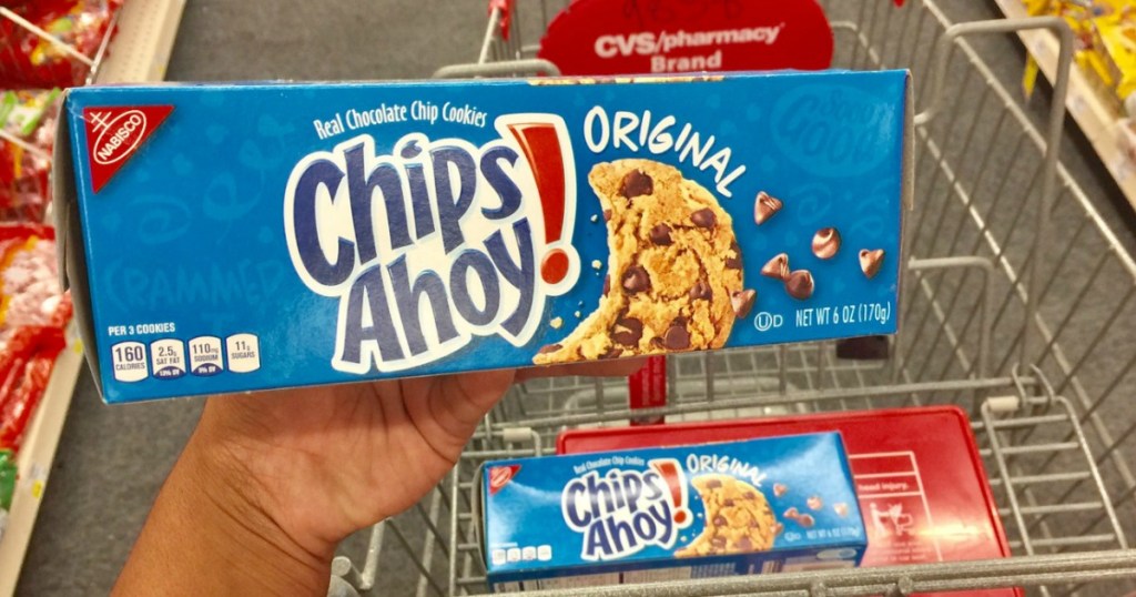 hand holding chocolate chips ahoy! cookies in store above a shopping cart