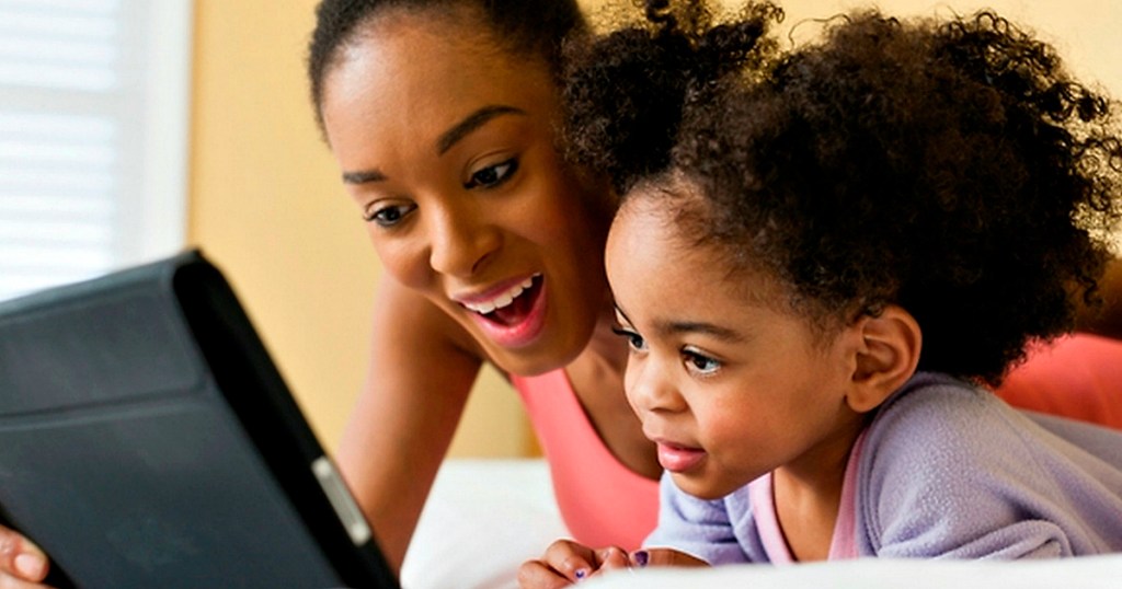 mother and daughter reading together on tablet