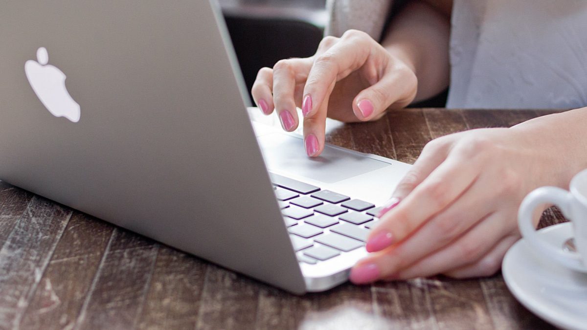 woman with pink nail polish using a laptop