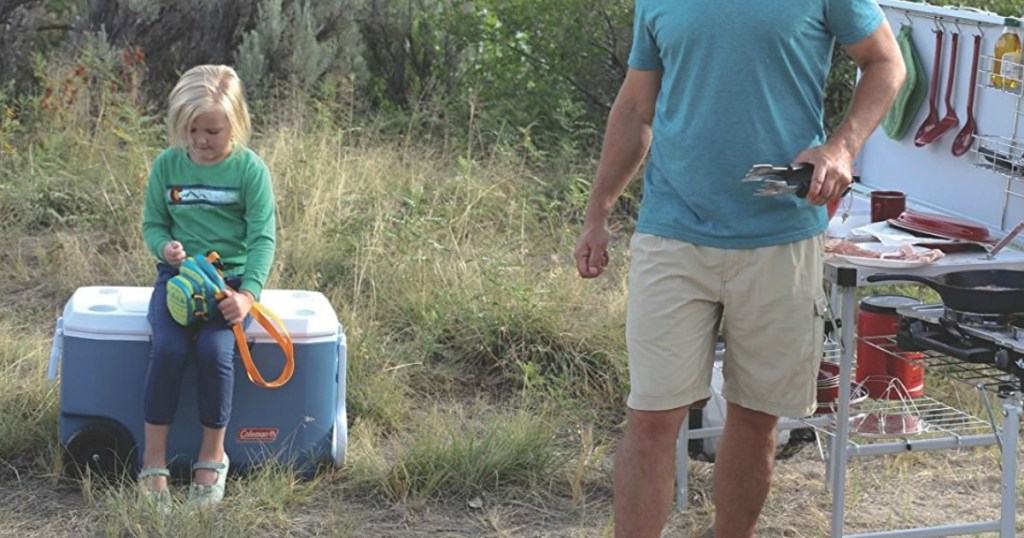 kid sitting on cooler in field 