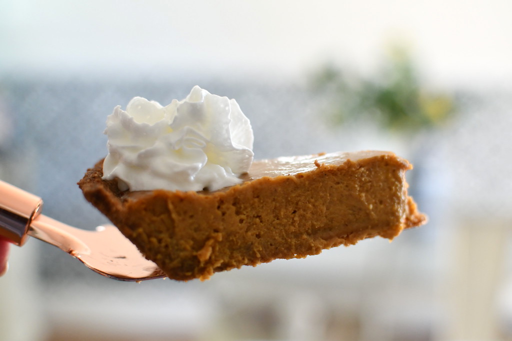 pumpkin pie slice with whipped cream on spatula 