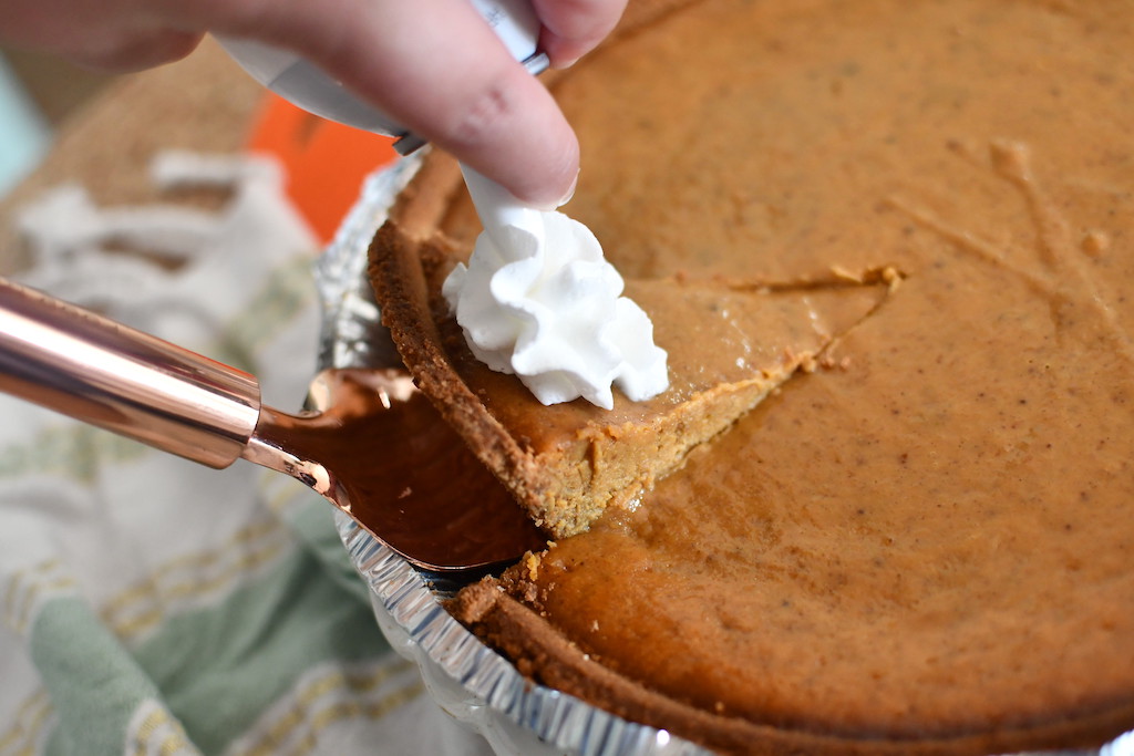 taking out pumpkin pie slice with whipped cream