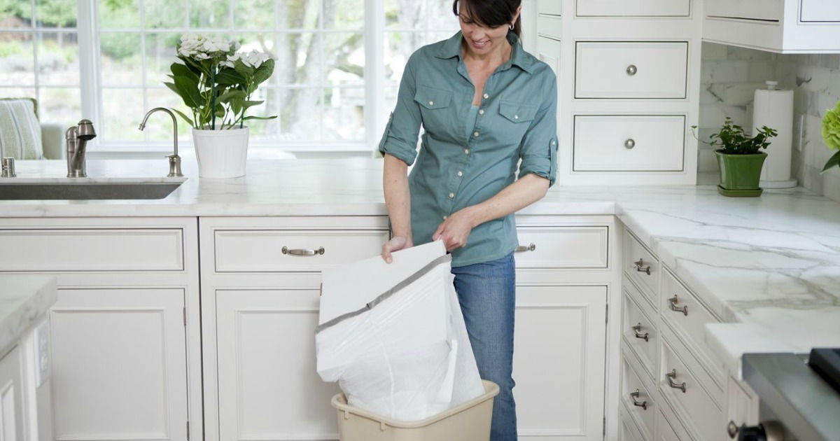 woman standing in kitchen changing her Glad Trash garbage bag