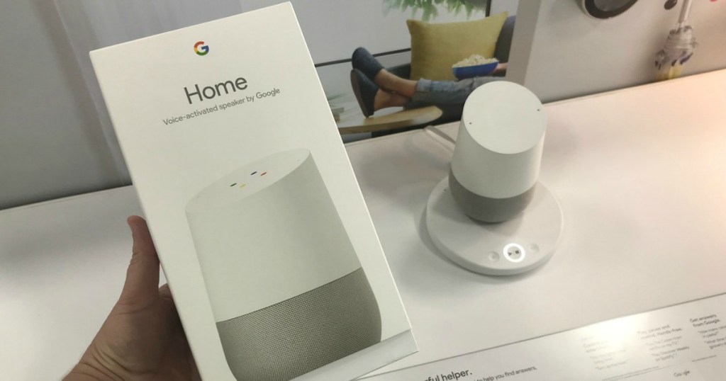 hand holding Google Home Speaker box with Google Home Speaker on display in background