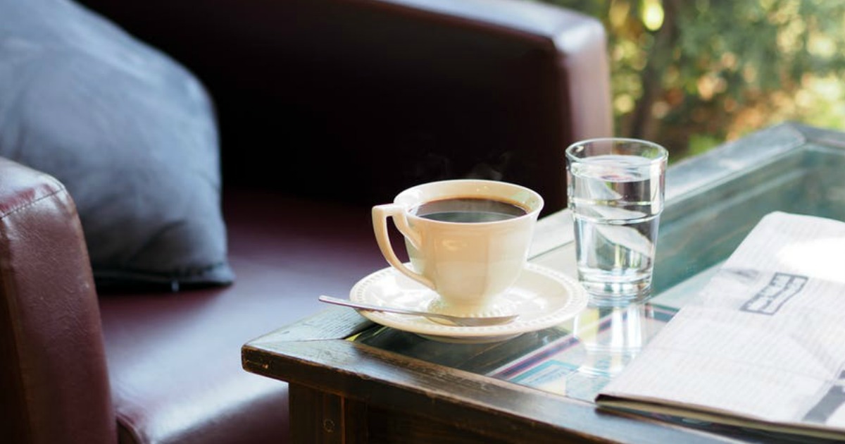 coffee and water on coffee table in front of an armchair