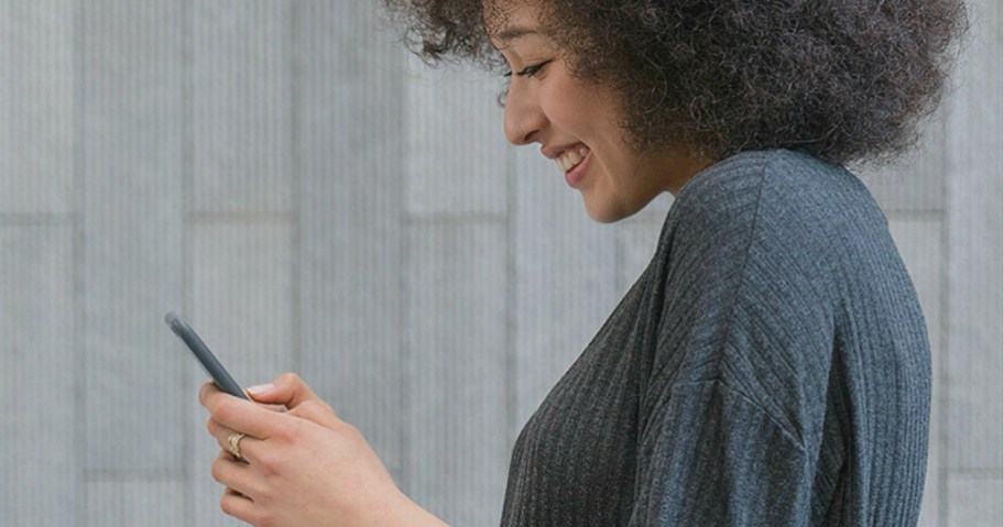 woman smiling while looking at her phone