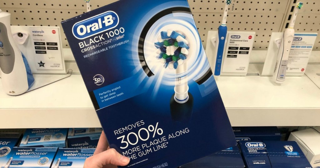 hand holding oral b toothbrush in front of shelf