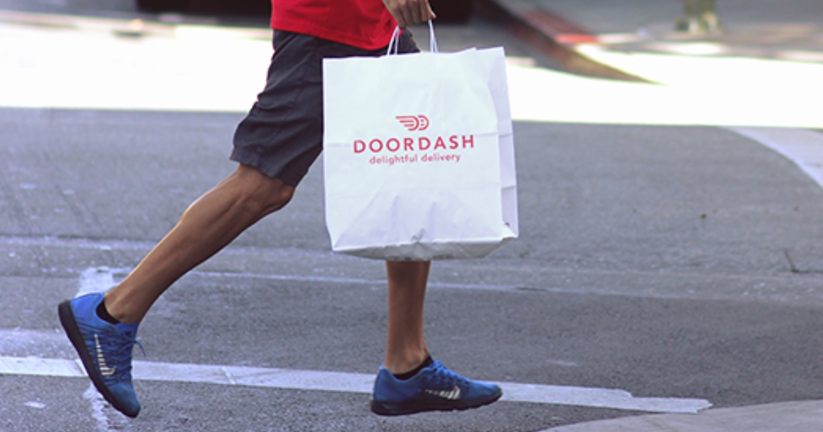 man walking and carrying a DoorDash delivery bag