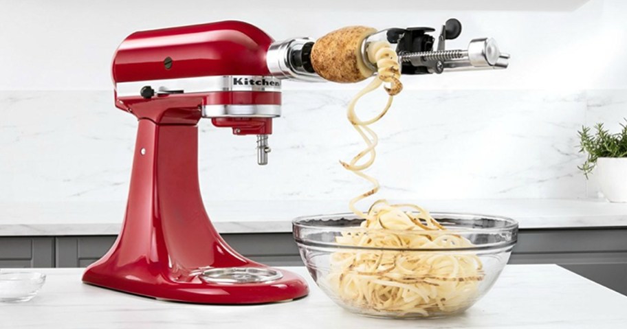 red kitchenaid with spiralizer spiraling a potato into bowl on counter